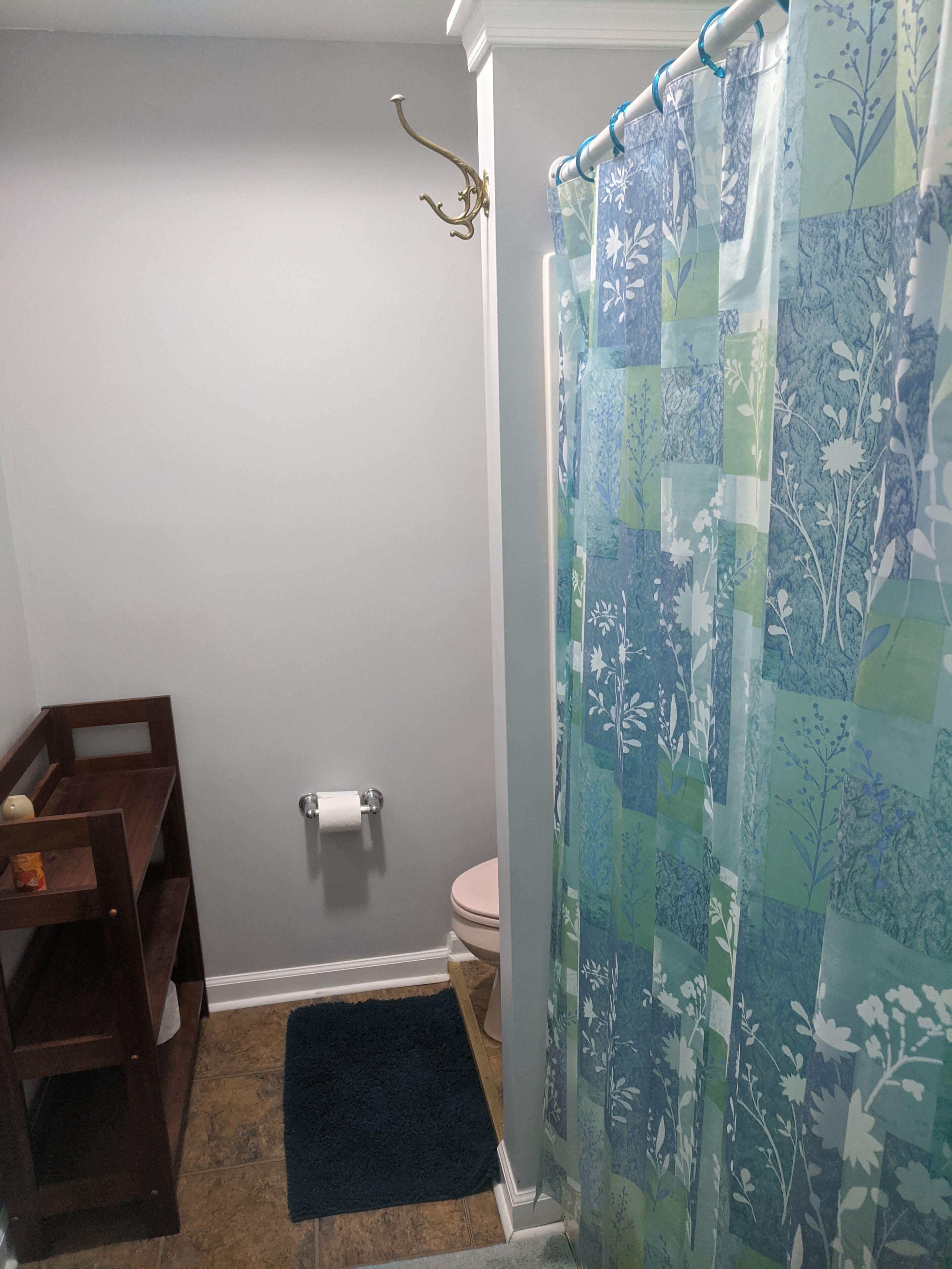 Une salle de bain avec un rideau de douche, des toilettes et un banc en bois.