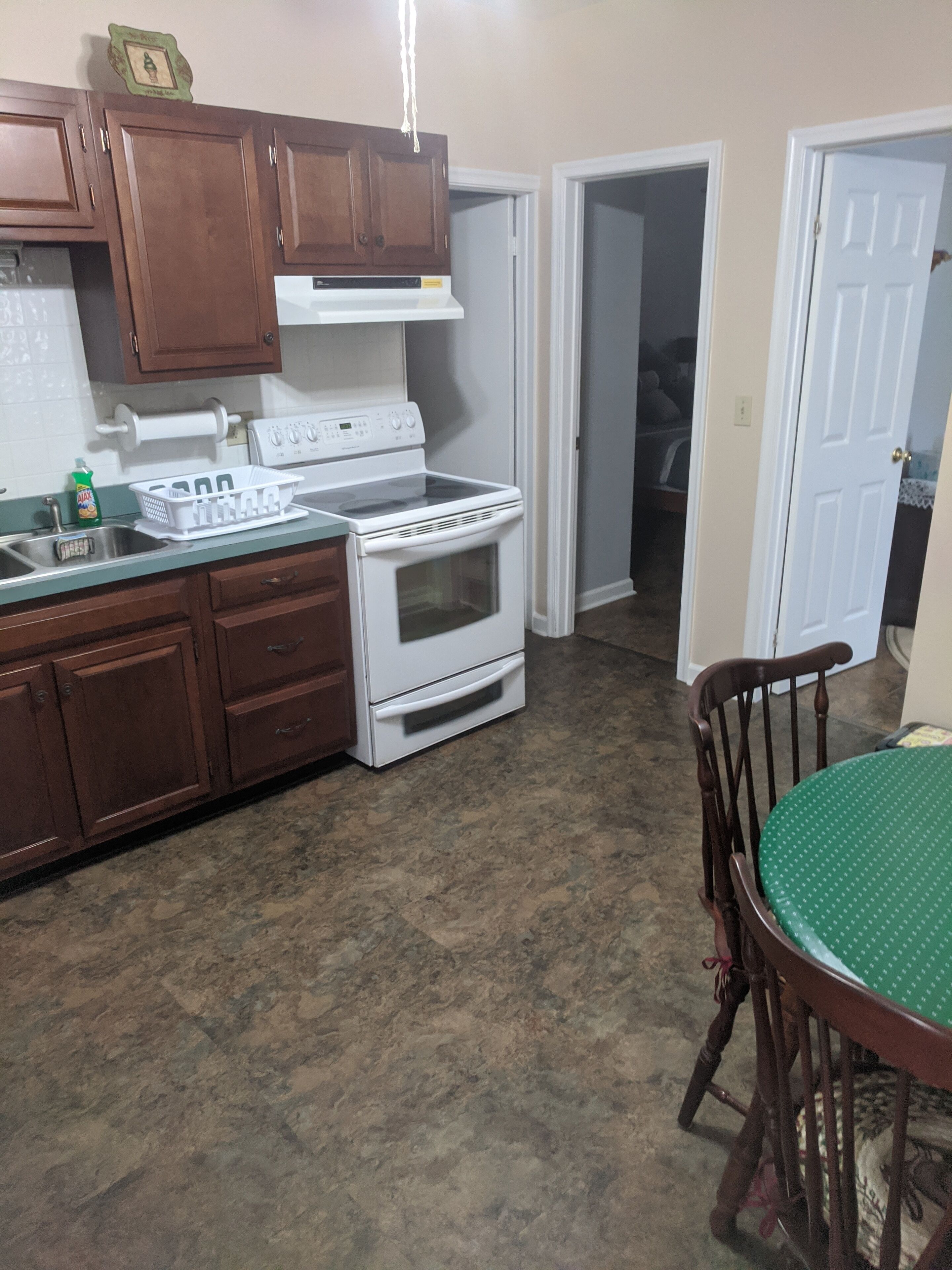 A kitchen with wooden cabinets, a white stove, and a green table.