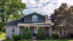 Une maison à deux étages avec un porche à l’avant, un garage et une pelouse bien entretenue.