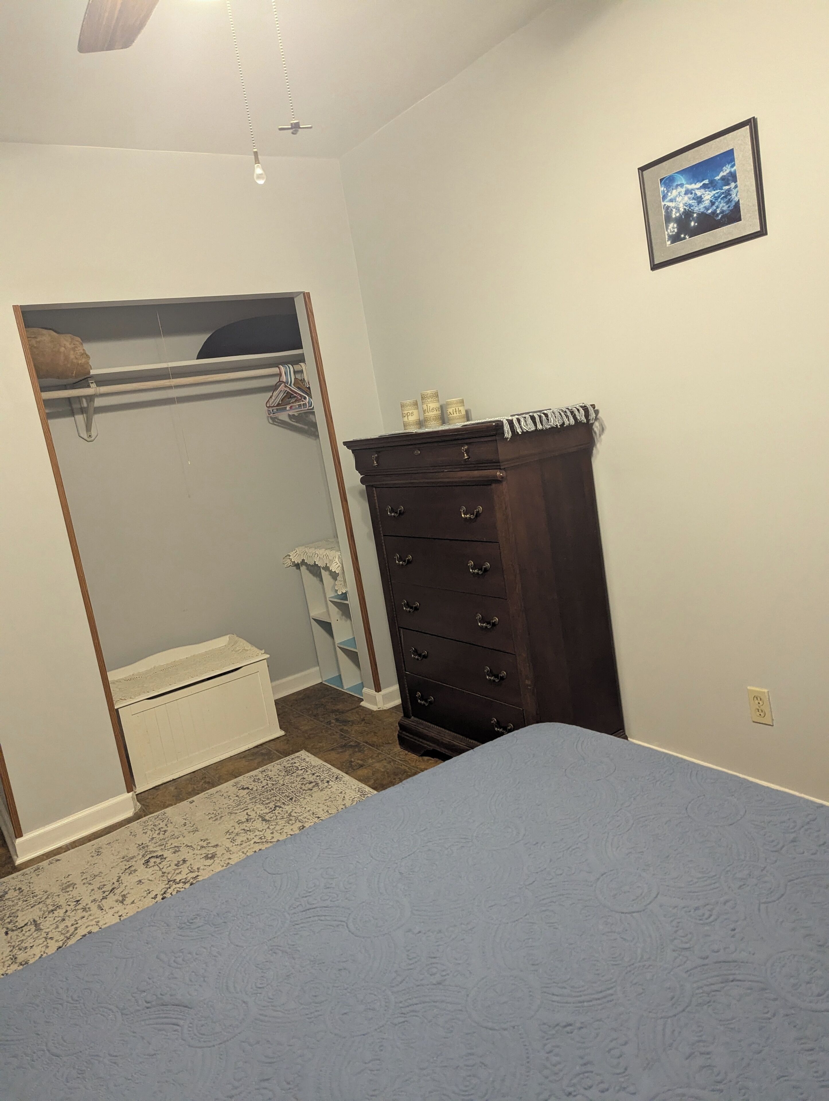 A bedroom with a bed, a dresser, a closet with a mirror, and a framed picture on the wall.
