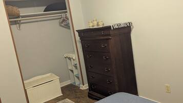 A bedroom with a bed, a dresser, a closet with a mirror, and a framed picture on the wall.