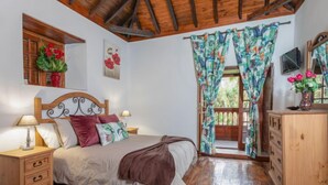 Un dormitorio con cama de madera, mesitas de noche, cómoda y ventana con cortinas.