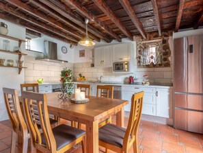 Une cuisine rustique avec une table à manger en bois, des chaises et un mur en pierre.
