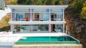 Une maison moderne à deux étages, dotée d’une piscine, de grandes baies vitrées et d’un balcon.