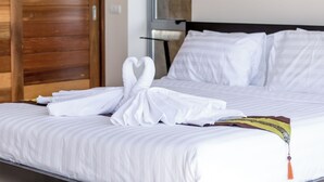 Un lit bien fait, avec du linge de lit blanc et une serviette décorative joliment disposée.