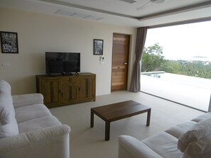 A living room with a television on a wooden cabinet, a coffee table, and two white sofas.