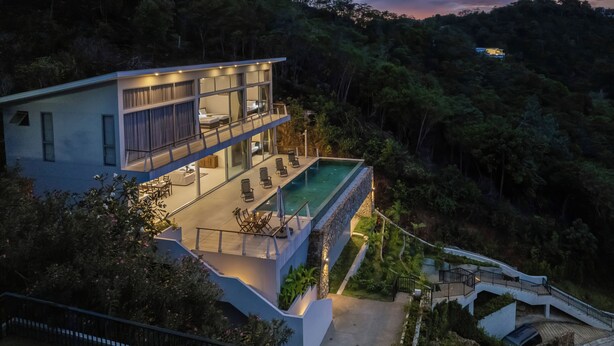 Une maison moderne à deux étages dotée d’un grand balcon et d’une piscine.