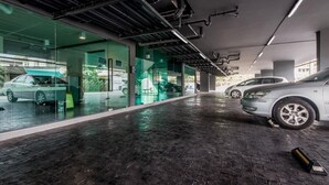 Un estacionamiento interior moderno con paredes de vidrio, suelo mojado y automóviles estacionados.