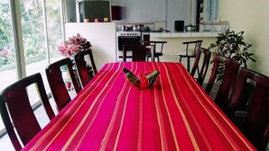 A dining area with a red-striped table, chairs, and a kitchen in the background. - ARCO House, La Marina. Saint Charles (San Carlos)