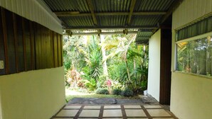 A hallway with a tiled floor leading to a covered outdoor area with lush greenery. - ARCO House, La Marina. Saint Charles (San Carlos)