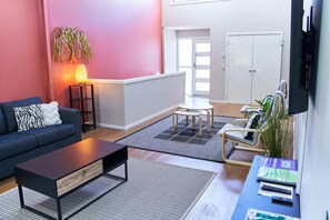 A modern living room with a sofa, coffee table, and a small dining area with chairs. - Treetops Haven- Bushland setting a short stroll to Maleny Centre (Maleny)