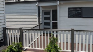 Een gebouw met twee verdiepingen, met een witte gevel, een duidelijke deur en een klein portaal met een witte balustrade.