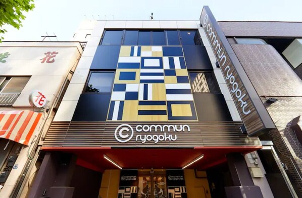 Un edificio con una facciata moderna, che presenta un logo e una segnaletica ben visibili per 'Commun Ryogoku'.