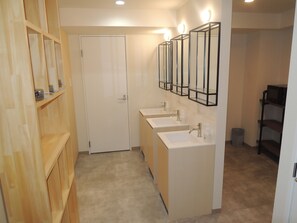 Un bagno con tre lavandini, scaffali in legno e una porta.