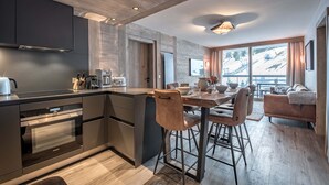 A modern kitchen with a central island, bar stools, and a dining table. - Winter Courchevel / Phoenix 502, proche commerce (Courchevel)