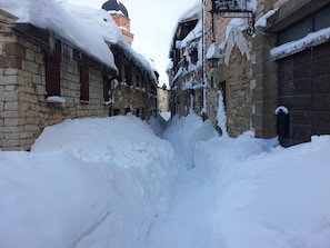 A narrow snow-covered alley between buildings with stone walls and wooden doors. - Viti Attic - A glimpse of Frontone Castle (Frontone)