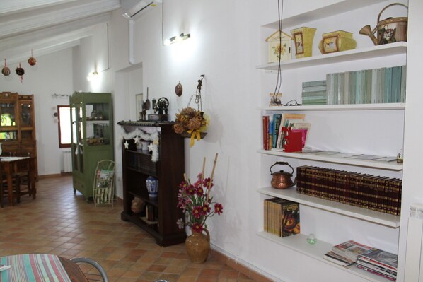 A room with a dining area, a bookshelf, and a kitchen area.