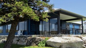 Una casa moderna con porche cubierto, ventanas amplias y una pared de piedra.
