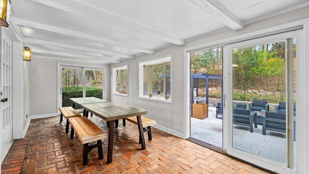 Um quarto espaçoso com uma grande mesa de madeira e bancos, janelas amplas e vista para o exterior.