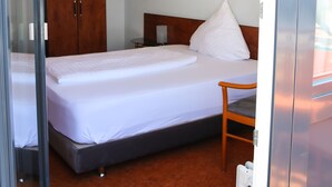 Habitación de hotel con cama, armario de madera, mesita de noche y un cuadro enmarcado en la pared.