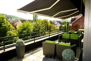 A balcony with wicker furniture and a view of a hillside. - Hotel Alpha (Stuttgart)