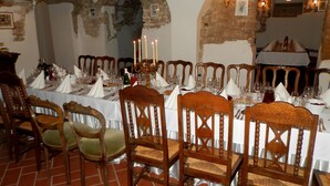 A dining area with a long table set for a meal, wooden chairs, and a brick floor. - Dwor Strzyzew (gmina Kampinos)