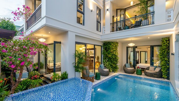 A modern hotel with a large indoor pool, multiple balconies, and lush greenery. - Volar de Faifo Villa (Da Nang)