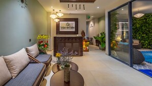 A reception area with a reception desk, sofas, a fireplace, and a view of a pool. - Volar de Faifo Villa (Da Nang)