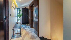 A hallway with a wooden bench, a potted plant, and a door with a 'JF' sign. - Volar de Faifo Villa (Da Nang)