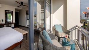 A hotel room with a bed, a desk, wicker furniture, and a balcony with a railing. - Volar de Faifo Villa (Da Nang)