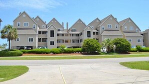 A multi-story residential building with a symmetrical facade, multiple balconies, and a central courtyard. - Cape Coddages I 101 - Oceanfront in Surfside Beach (Surfside Beach)