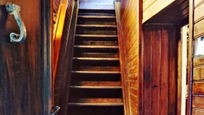 A wooden staircase with a metal handrail and a door with a decorative handle. - At casa di u piratu (FARINOLE)