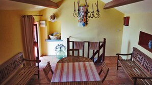 A dining area with a wooden table and benches, a chandelier, and a view of the kitchen. - At casa di u piratu (FARINOLE)