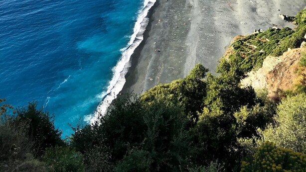 A coastal landscape with a beach, mountains, and vegetation. - At casa di u piratu (FARINOLE)