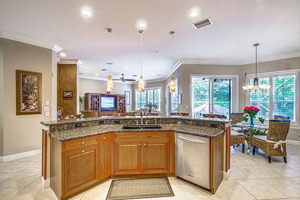 A spacious kitchen with a large island, wooden cabinets, and pendant lighting.