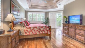 Un dormitorio con cama, cómoda, televisor y ventilador de techo.