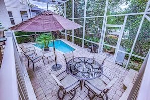 An outdoor patio with a pool, seating area, and a large umbrella.