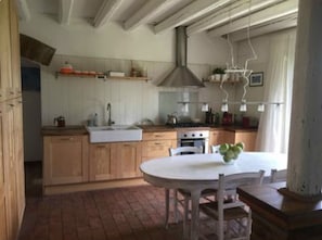 A kitchen with wooden cabinets, a white countertop, and a hanging light fixture.