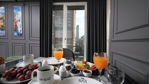Una mesa de desayuno con platos, tazas y vasos de zumo de naranja, con vistas a la ciudad.