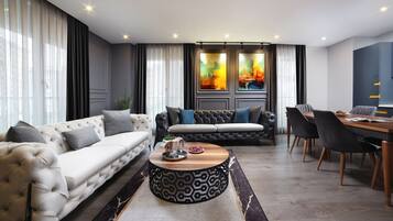 A modern living room with a sofa, a coffee table, and a dining area with chairs and a table.
