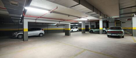 Uma garagem de estacionamento com vários níveis, pisos de concreto e linhas amarelas demarcando as vagas.