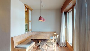 A dining area with a wooden bench seating, a table, and a pendant light. - Very well located apartment house in the favorite and quiet Salet area. (St. Moritz)
