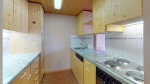 A kitchen with wooden cabinets, a sink, a dishwasher, and a stove. - Very well located apartment house in the favorite and quiet Salet area. (St. Moritz)