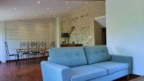 Una sala de estar con un sofá azul claro, una mesa de comedor con sillas y una pared decorativa de estilo rústico.
