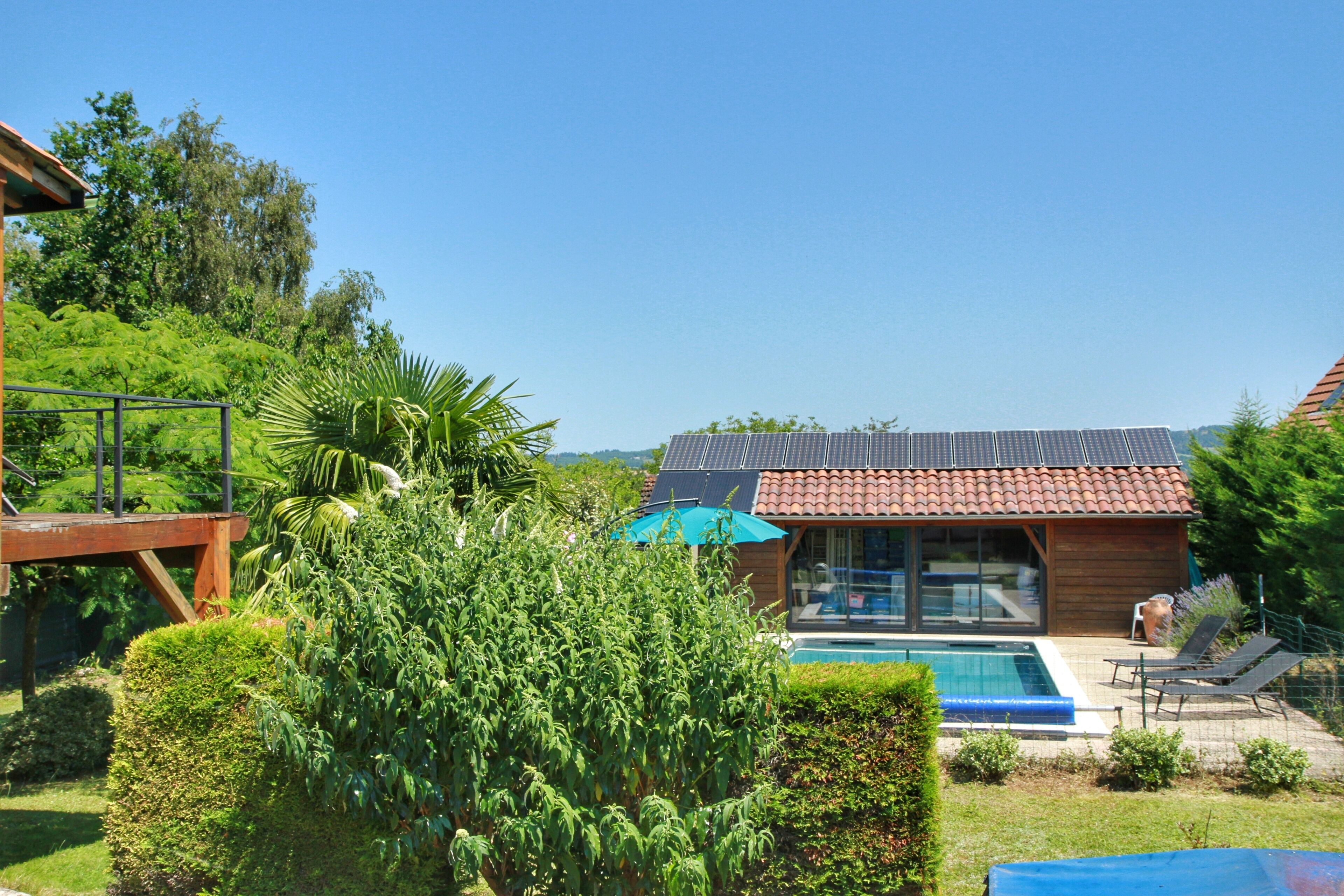 Ein modernes Haus mit Schwimmbad, umgeben von üppiger Vegetation und einer Holzterrasse.