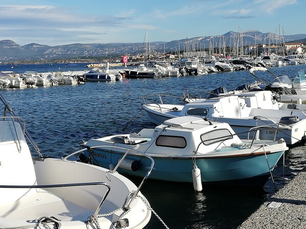 Un port de plaisance où sont amarrés plusieurs bateaux, un ciel dégagé et un paysage montagneux en arrière-plan.