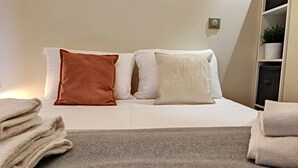 A neatly made bed with white and brown pillows, a grey blanket, and folded towels on the side. - N&J - KORNER AVENUE TERRACE - Hyper center (Niza)
