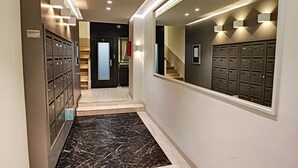 A hallway with lockers, a marble floor, and a staircase leading to another area. - N&J - KORNER AVENUE TERRACE - Hyper center (Niza)