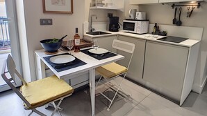 A compact kitchen with a dining area, including a table with chairs, a microwave, a coffee maker, and a sink. - N&J - KORNER AVENUE TERRACE - Hyper center (Niza)