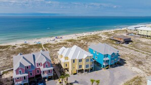 A beachfront property with multiple colorful houses, a sandy beach, and the ocean in the background.